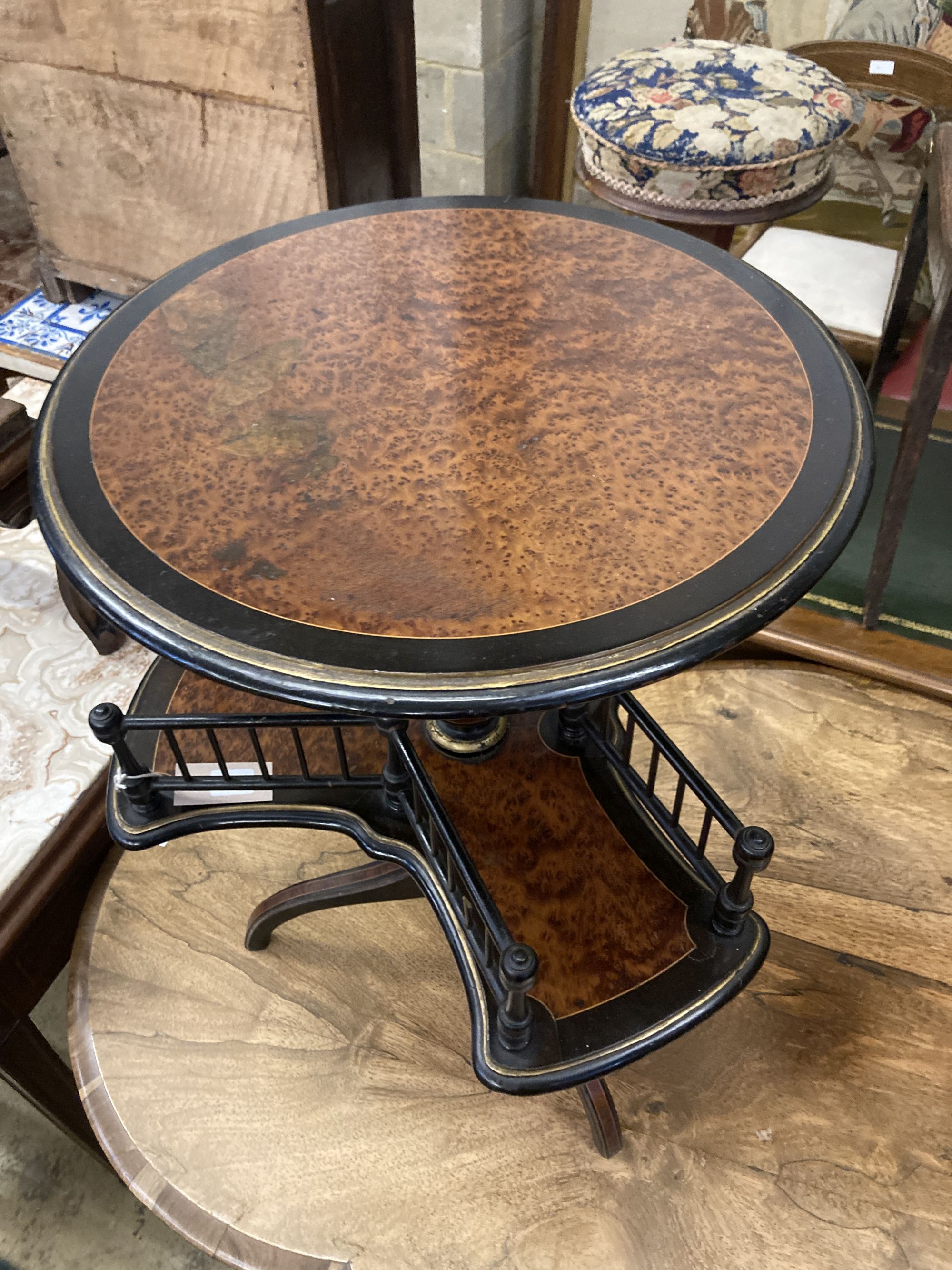 An ebonised and gilt thuya or walnut book table, the circular top over revolving trefoil book rack